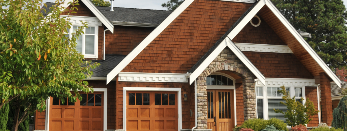 A cottage-themed house with a red, brick exterior and white trim.