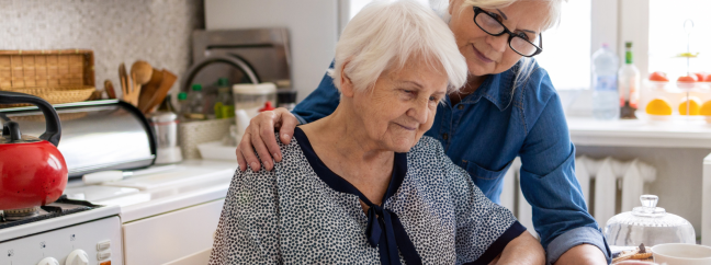 Two senior woman in a kitchen reviewing papers together.