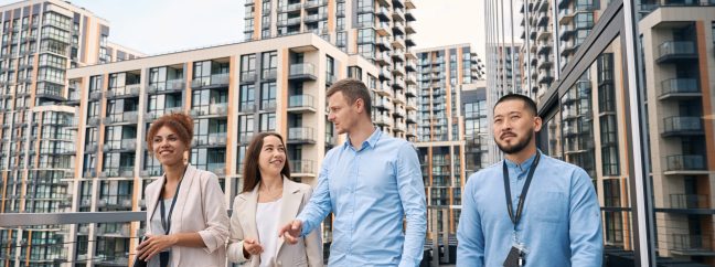 Multiethnic team of young stylish corporate workers strolling together on office balcony