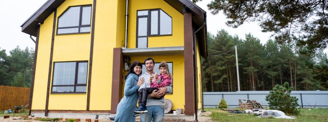 Happy family in the yard of an unfinished house - purchase of a cottage, mortgage, loan, relocation, construction