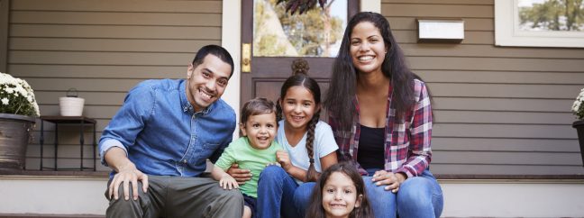 Portrait Of Family Sitting On Steps in Front Of House