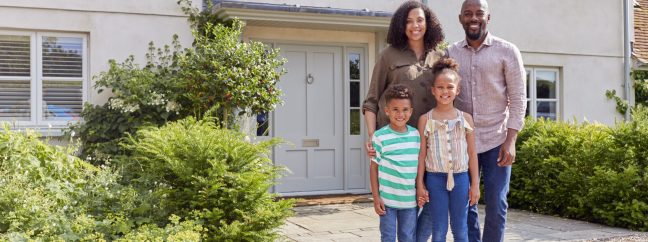 Portrait Of Smiling Family Standing Outside Home Together