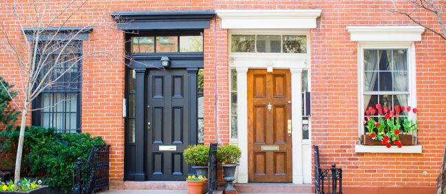 Two contrasting doors of townhouses. The townhomes are made of red brick.