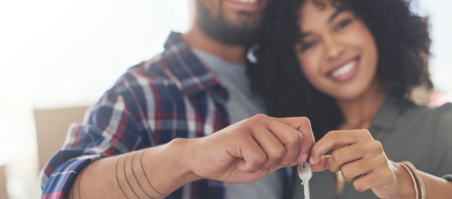 couple in front of first home with key